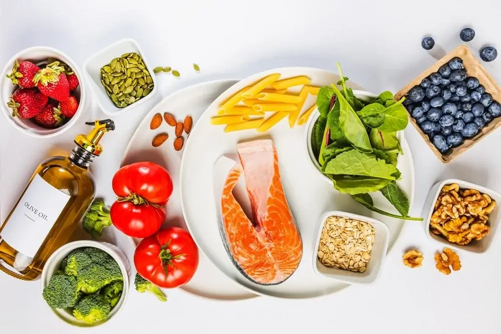 Composizione di cibi antinfiammatori naturali: frutti di bosco, salmone, olio d'oliva e noci per la prevenzione e il benessere cellulare